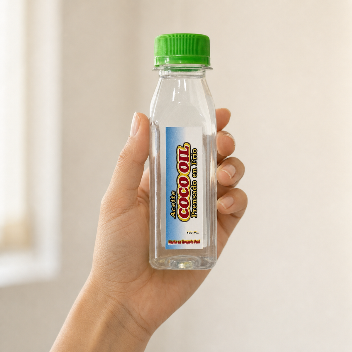 Coco Oil (100 ml) — el envase sostenido en una mano, para ver su tamaño real